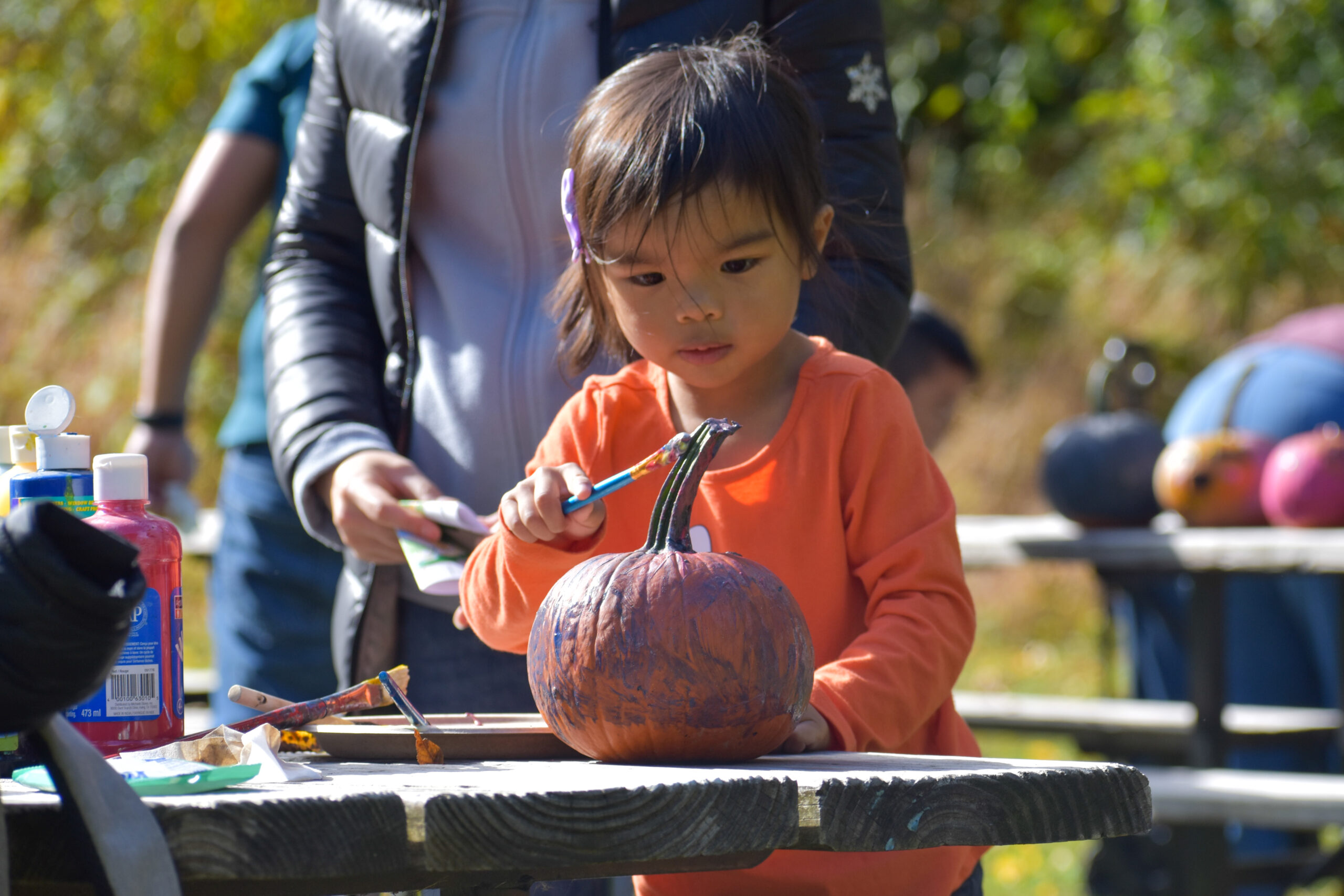 child painting pumpkin at family event